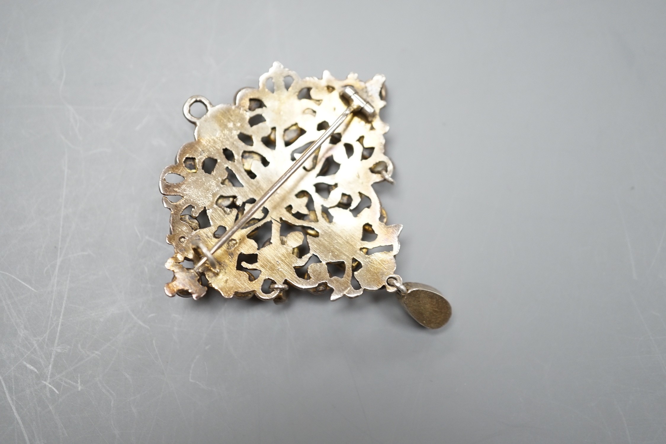 An Indian? gilt white metal and multi gem set drop pendant brooch, (stone missing), 54mm.
